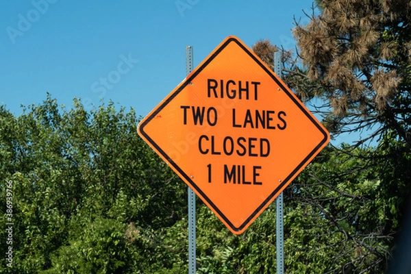 Obraz Bright orange Diamond shape sign ways "right two lanes closed 1 mile" on metal post with
