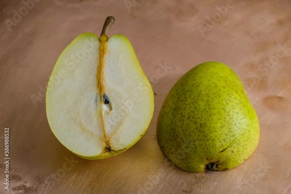 Fototapeta Two halves of ripe green pear on a copper surface.