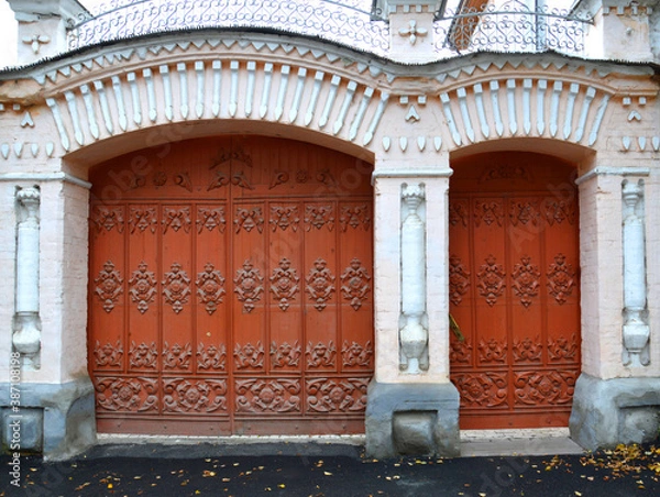 Obraz Carved antique gate and doors to a stone mansion. Folk crafts.  Delicate wood carving with plant motifs. Emergency entrance to the administration of the city of Alapaevsk, Sverdlovsk region, Russia.