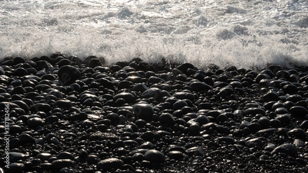 Obraz Waves on the shore of a black pebble beach