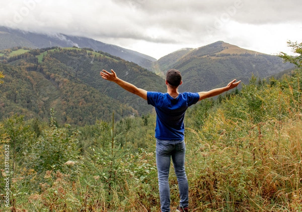 Obraz A happy man is standing on the top of the mountain and enjoying the beautiful view. Photographed on foggy weather in the Tatras, Slovakia.