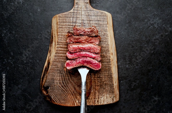Fototapeta Different degrees of roasting steak on a meat fork on a stone background