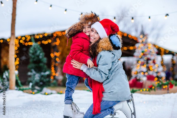 Obraz Portrait of a girl in Russian cap posing with her mom on the ice rink.