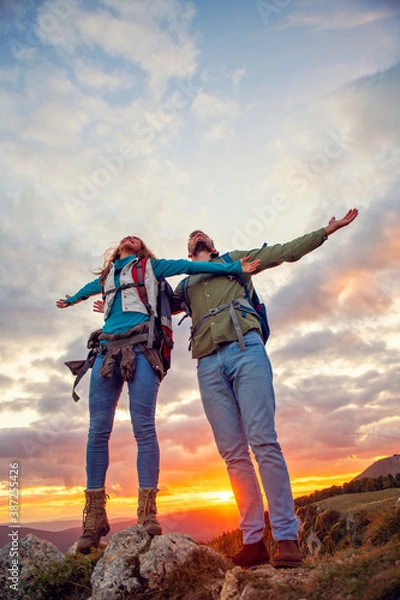 Fototapeta Couple on Top of a Mountain Shaking Raised Hands