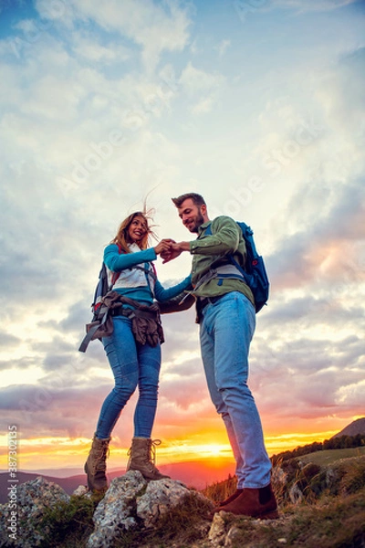 Fototapeta Couple on Top of a Mountain Shaking Raised Hands