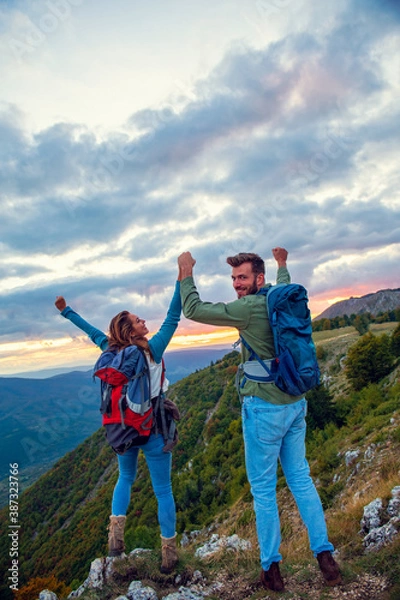 Fototapeta Couple on Top of a Mountain Shaking Raised Hands