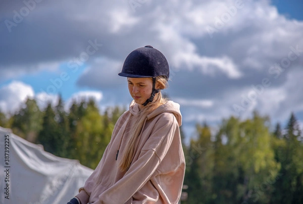 Obraz Portrait of a girl in a helmet against a cloudy sky.
