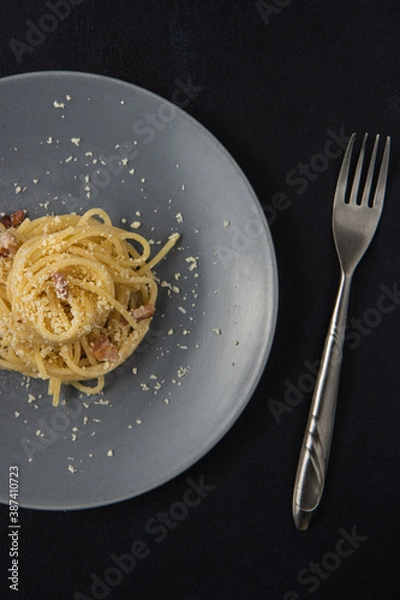 Obraz Traditional Italian dish spaghetti carbonara with bacon in a cream sauce in a plate over dark background. Top view with copy space. Served and ready to eat.