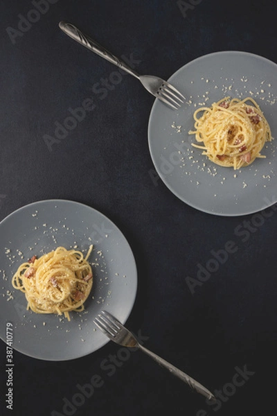 Obraz Two portions of Spaghetti traditional Italian dish spaghetti carbonara with bacon in a cream sauce in a plate over dark background. Top view with copy space.