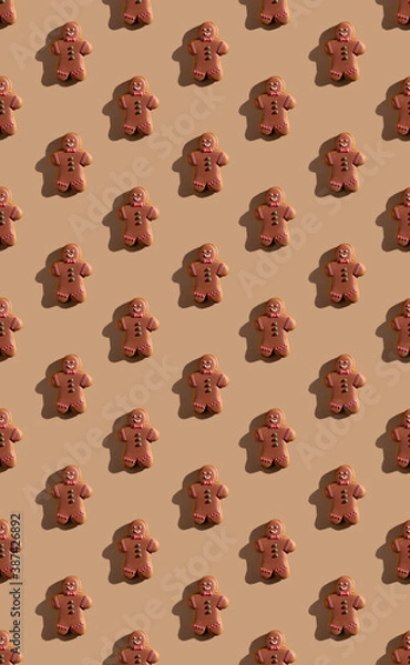 Fototapeta gingerbread pattern. Christmas bakery decor. Festive food background. Biscuit figure man with chocolate icing colorful ornament isolated on beige pastel.