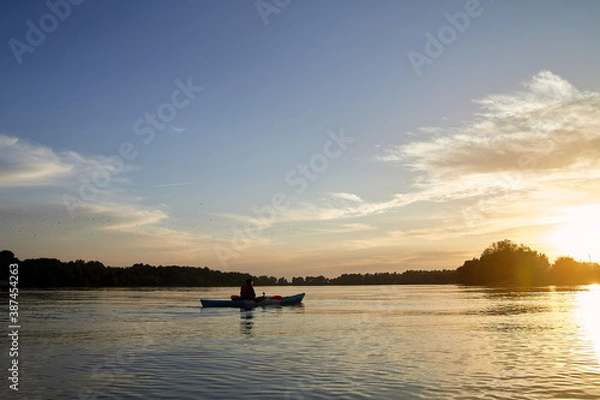 Fototapeta Sillouette of man kayaking on the Danube river at sunset