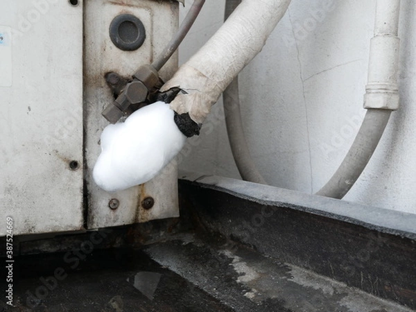 Obraz air pipes covered by frozen on air conditioner compressor outside building.