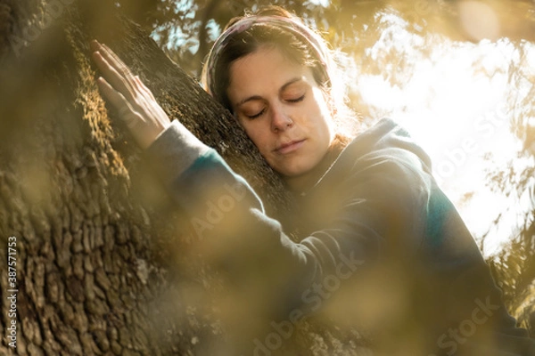 Fototapeta Close portrait of woman hugging the trunk of an old oak tree