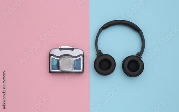 Fototapeta Mini audio cassette player with stereo headphones on a blue pink background. Top view