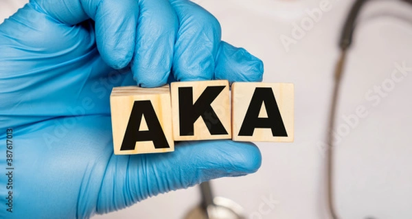 Fototapeta AKA Above the knee amputation. - word from wooden blocks with letters holding by a doctor's hands in medical protective gloves. Medical concept.