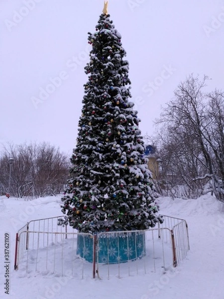 Obraz Christmas tree in snow and toys stands in the Park waiting for the new year