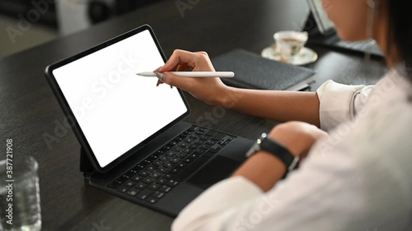 Fototapeta A young businesswoman using stylus pen pointing on screen digital tablet while sitting in office.