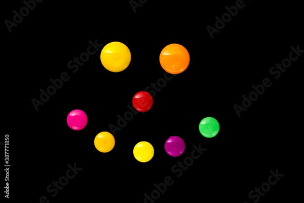 Fototapeta The outline of a smile is made of colored plastic magnets on a black background (top view).