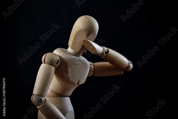 Fototapeta A portrait of a wooden mannequin showing emotion like sadness, loneliness, fear and depression on black background.