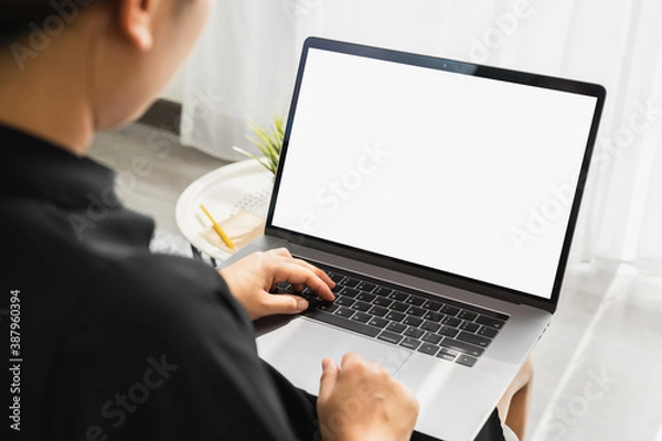 Fototapeta Hand using laptop with blank copy space screen for your advertisement. on the table in office.