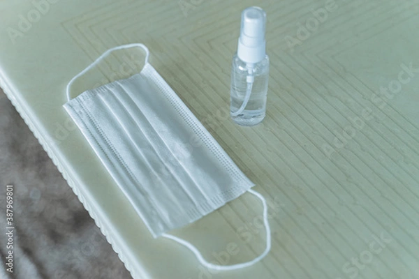 Fototapeta a mask and a hand sanitizer on a table