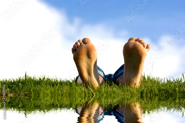 Fototapeta Feets na trawie w pobliżu wody.