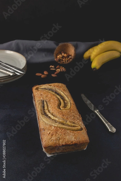 Obraz Banana nut bread loaf isolated on the dark background. Banana bread ingredients. Homemade delicious pastries. Front view.