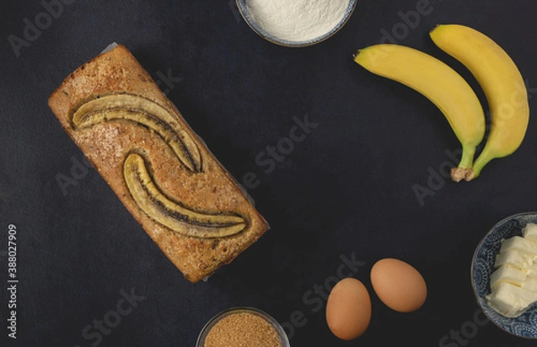 Obraz Homemade banana nut bread loaf isolated on the dark background. Banana bread ingredients. Top view, flat lay.