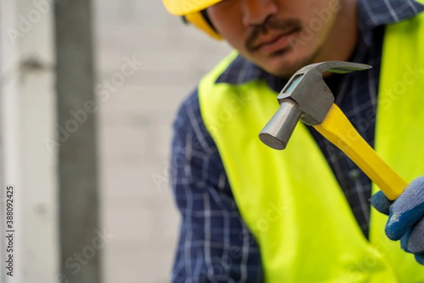 Fototapeta industrial worker building exterior walls in the house under construction,Using hammer for laying bricks in cement.