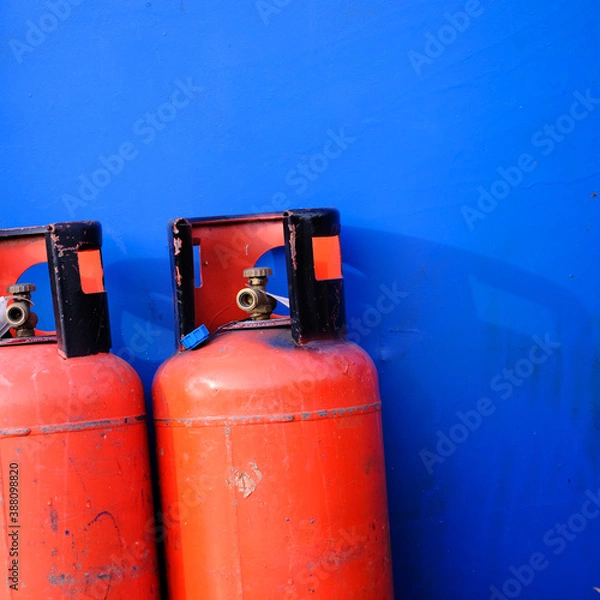 Fototapeta abstract image of two red gas bottles against a blue background