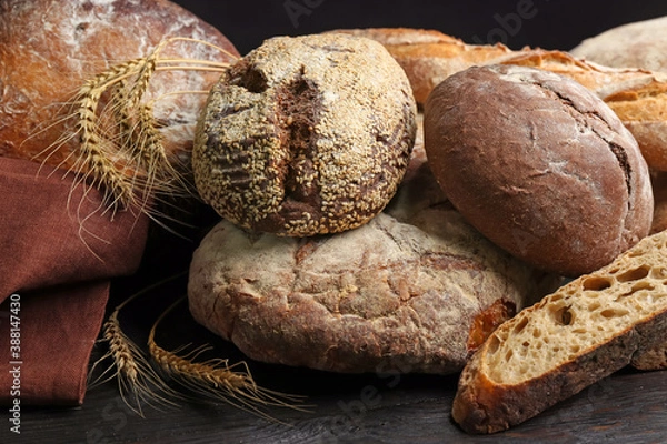 Fototapeta Different kinds of fresh bread on black wooden table, closeup