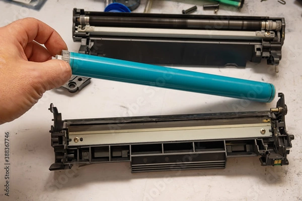 Fototapeta the hand of the service center master holds an organic selenium photoreceptor by the gear while refilling the laser printer cartridge