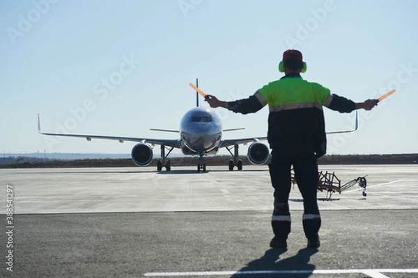 Fototapeta The runway traffic controller uses gestures and sticks to help the aircraft choose the correct trajectory around the airfield