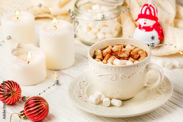 Fototapeta Coffee, cocoa, hot chocolate with marshmallows and cinnamon in a white Cup on a wooden table. New year. The concept of comfort and relaxation with candles, spices and Christmas toys. Selective focus