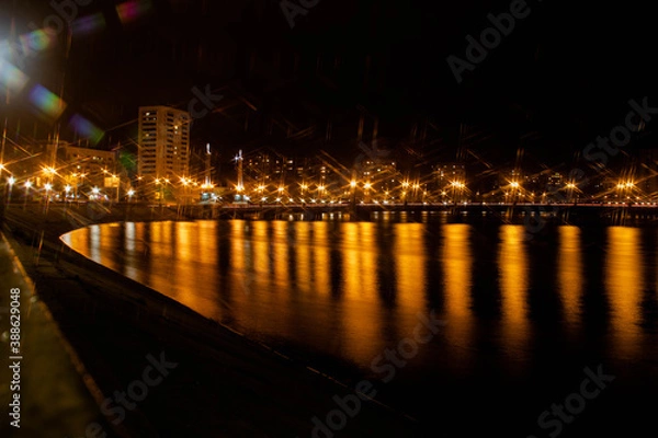 Fototapeta Night city view of the old bridge across the river lanterns six-pointed stars with smooth water reflections
