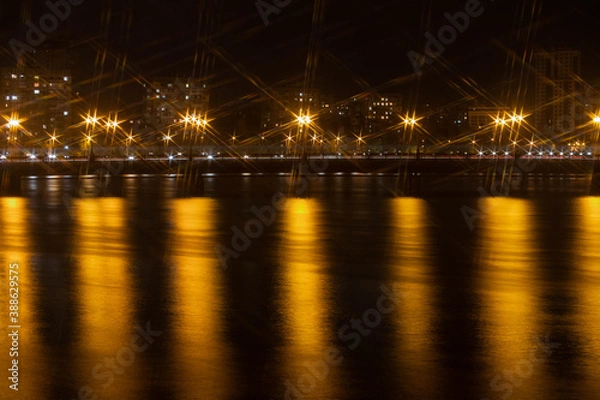 Fototapeta Night city view of the old bridge across the river lanterns six-pointed stars with smooth water reflections