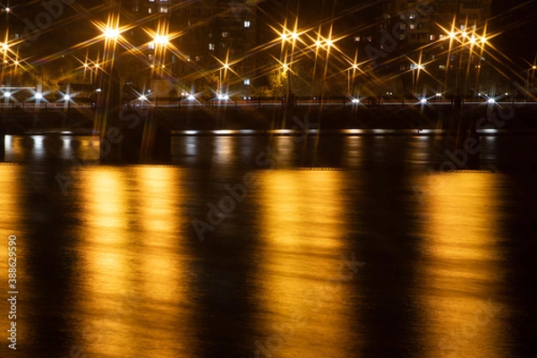 Fototapeta Night city view of the old bridge across the river lanterns six-pointed stars with smooth water reflections