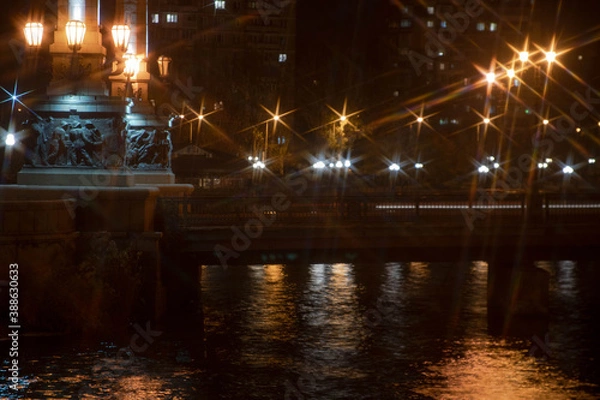 Fototapeta Night city view of the old bridge across the river lanterns six-pointed stars with water reflections