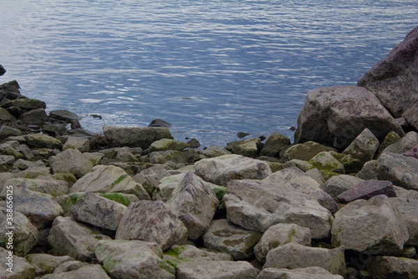 Fototapeta View of the shore with gray rocks and blue water