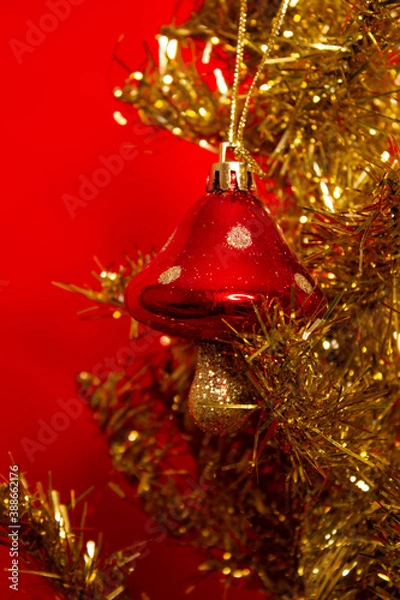 Fototapeta Christmas toy red and gold fly agaric on a Golden Christmas tree on a red background