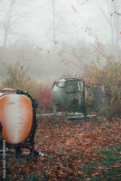 Fototapeta old farm equipment sitting in a field with a drape of fog around 