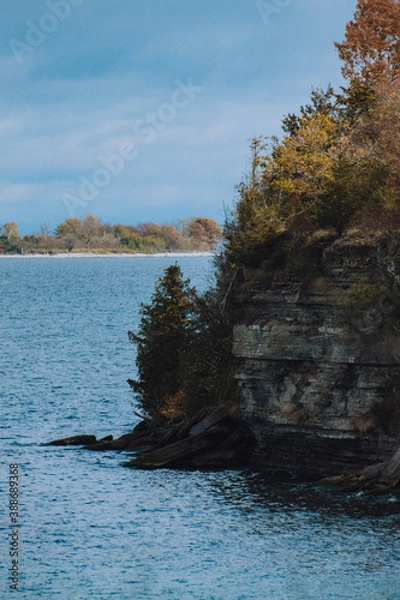 Fototapeta sheer cliff edge with trees and water around