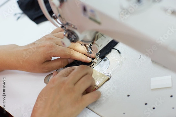 Obraz The worker is sewing a textile with a sewing machine in a fabric factory.