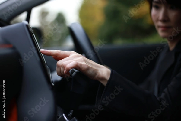 Fototapeta 運転中にカーナビを操作する女性