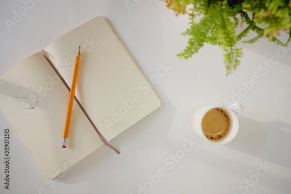 Fototapeta Top view of coffee cup and notebook on a white desk