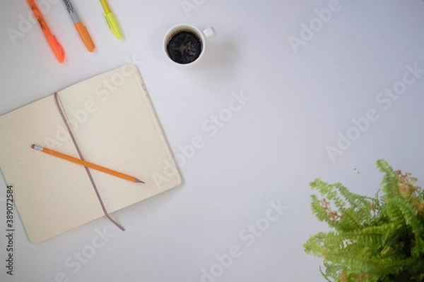 Fototapeta Top view of coffee cup and notebook on a white desk