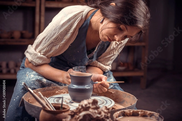 Fototapeta Beautiful ceramist working with pottery at the ceramic workshop. Making pottery.