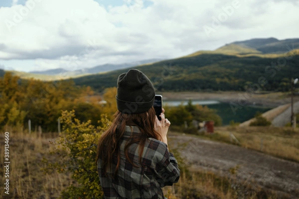 Fototapeta Traveler with a mobile phone in her hands on nature in autumn in the mountains