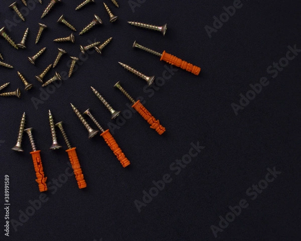 Fototapeta The abstract form and background for the text is made of screws and dowels on a black background (top view).