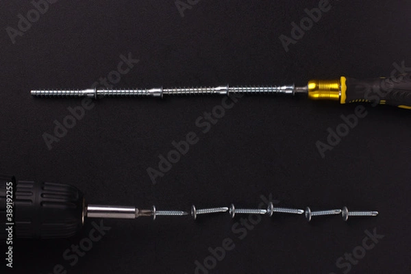 Fototapeta the background for the text is made of screws, furniture screws, a screwdriver, a screwdriver on a black background (top view).